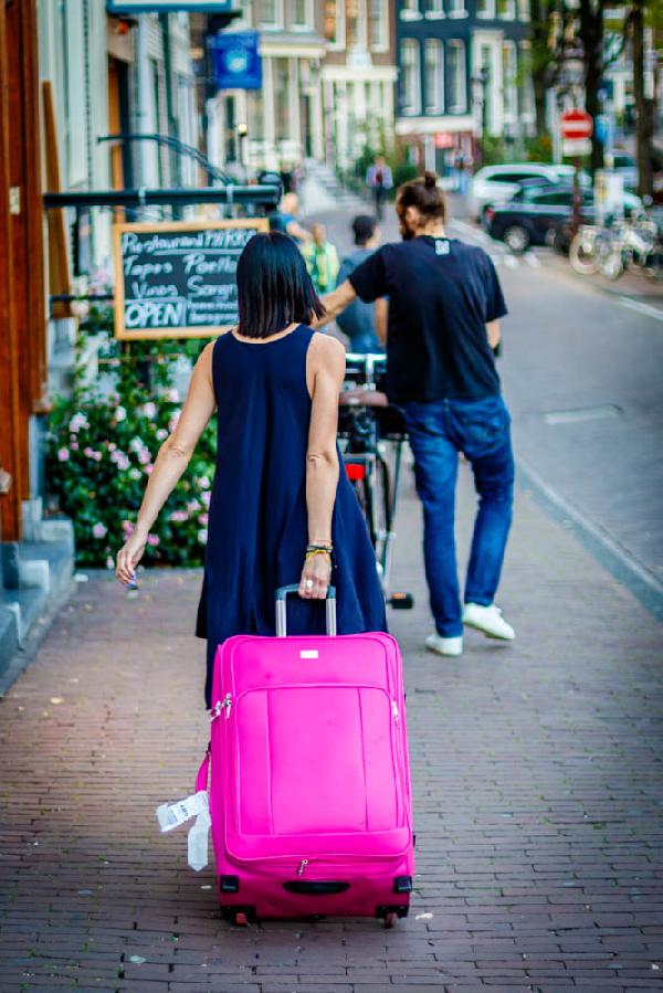 Streets of Amsterdam. Girl with pink suitcase.